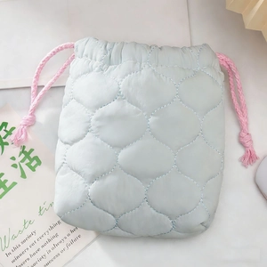 Detail van lichtblauwe gewatteerde tas met trekkoord en roze kwastjes voor camera