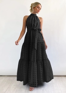 Detailed view of black tiered maxi dress featuring a halter neck and subtle checkered fabric
