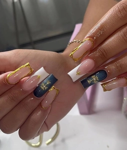Macro detail of long square nails featuring relief crosses and gold metallic borders