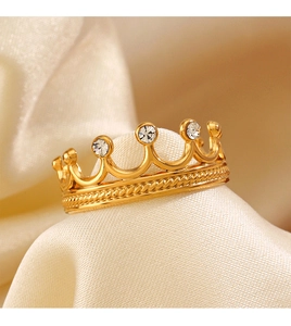 Détail macro de la bague couronne dorée avec zircons sur tissu en soie blanche