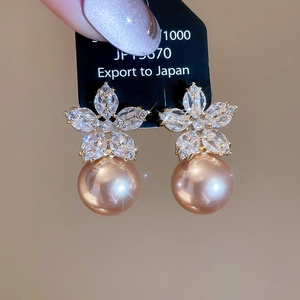 Detailed macro view of a zircon flower earring with a large champagne golden pearl