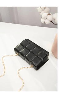 Detailed side view of black quilted faux leather crossbody bag with gold chain strap