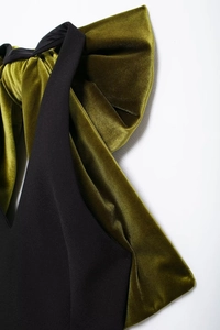 Vue détaillée du nœud en velours vert sur la robe de cocktail noire moulante