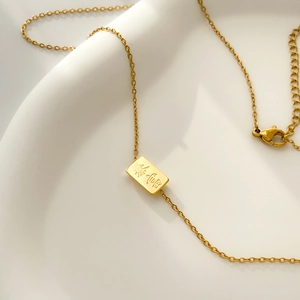 Close-up of gold plated stainless steel rectangular pendant with Gongxi engraving