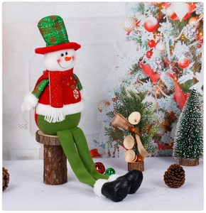 Detail of a Christmas snowman plush doll with long legs sitting on a wooden stump