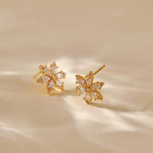 Detailed macro view of gold snowflake stud earrings inlaid with sparkling zircon stones