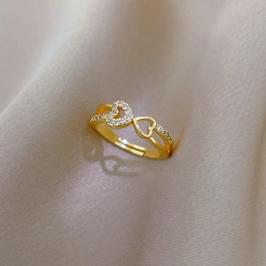 Close-up of gold double heart ring with zircon inlay on textured fabric background