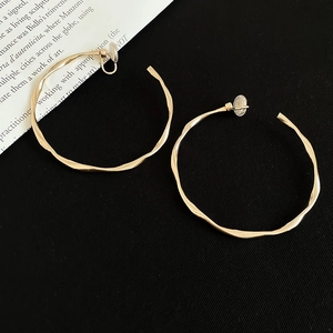 Detail of gold twisted hoop clip-on earrings with textured finish and soft pads