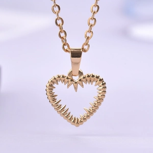 Macro shot of gold heart necklace pendant with unique serrated edges and O-chain detail