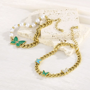 Detail of vintage gold butterfly charm bracelet with green enamel and pearls on silk