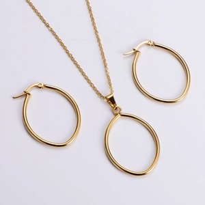 Macro shot of minimalist gold oval pendant necklace and matching earring jewelry set
