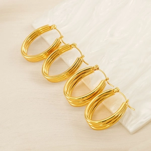 Detail of triple-layered golden hoop earrings on a white wavy display stand