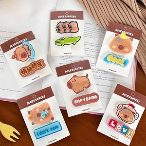 Close-up of cute Capybara hair clip set with 6 cartoon designs on cozy desk background