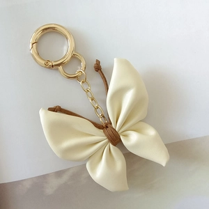 Detailed shot of cream leather butterfly keychain with gold hardware and brown accents