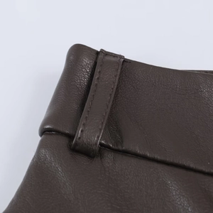 Vue macro du simili cuir marron foncé montrant les passants de ceinture et les coutures