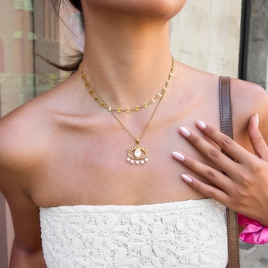 Double-layered gold evil eye necklace with clear zircon and pearl accents on female model