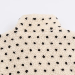 Gros plan sur tissu sherpa doux avec pois noirs sur fond crème de haute qualité