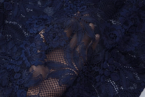 Gedetailleerde macro-opname van marineblauwe kantstof met florale patronen en textuur
