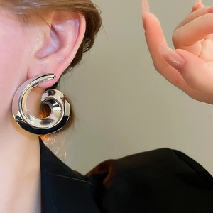 Close-up of model wearing silver spiral snail earrings with polished mirror finish
