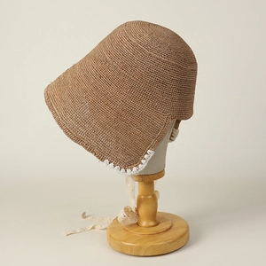 Close-up of handmade raffia sun hat with delicate white lace crochet and ribbon ties