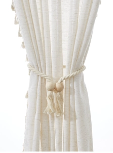 Detail of cream linen curtain with natural wood bead tassel tieback on white background