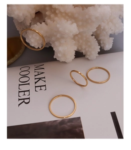 Macro shot of minimalist thin 18k gold rings displayed on white coral and magazine