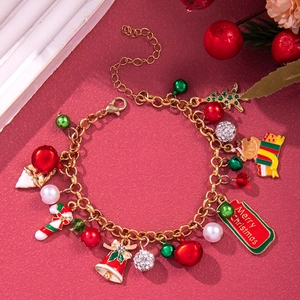 Detail of Christmas bracelet with Santa, bell and pearl charms on red background