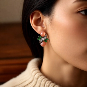 Close-up of vintage resin earrings with pink and green stones on a model's ear