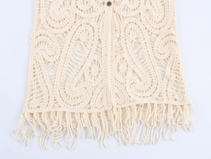 Dettaglio del motivo paisley all'uncinetto beige con frange spesse sul fondo della maglia