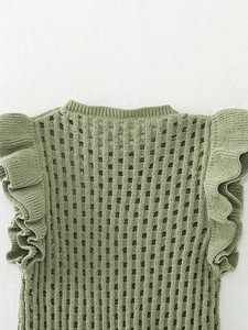 Détail du gilet en maille chenille vert herbe avec bordures à volants et motifs ajourés