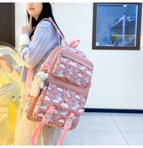 Pink nylon backpack featuring unicorn patterns and a white plush bear keychain accessory