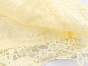Gros plan du tissu jaune clair avec des coutures en dentelle et broderie ajourée détaillée