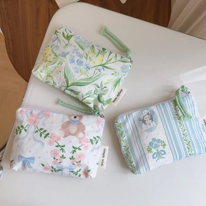Detailed view of floral cotton mini pouches with woven zipper pulls and side labels