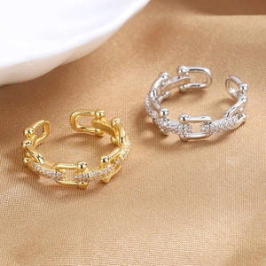 U-link chain rings in gold and silver with zircon pavé on luxurious gold satin fabric