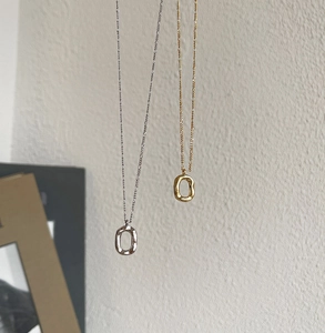 Detailed close-up of textured oval donut pendants in gold and silver hanging on fine chains