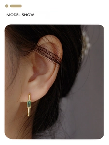 Close-up model view of vintage gold hoop earrings featuring square emerald green gemstones