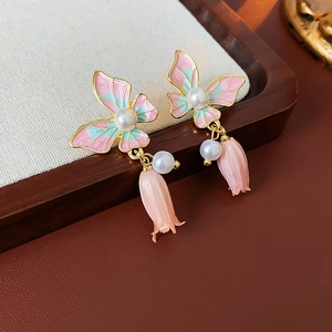 Detail of pink and green enamel butterfly earrings with hanging pearls and rosebud charms