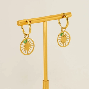 Detailed macro view of gold plated sun earrings with green stone on a display stand
