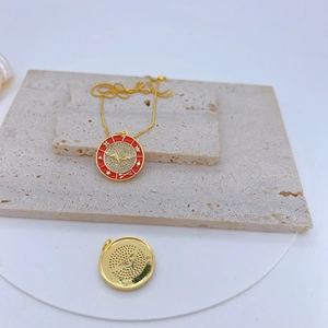 Macro shot of gold-plated evil eye pendant with red enamel, CZ heart and wing details
