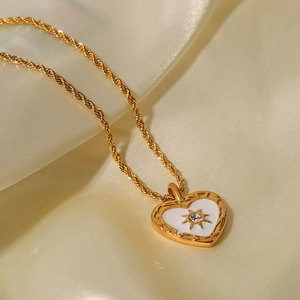 Nahaufnahme des Herzanhängers mit weißer Emaille und Zirkonia an einer goldenen Kordelkette