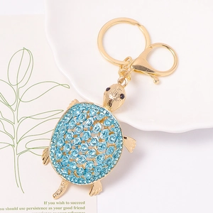Détail du porte-clés tortue en métal doré orné de strass bleus brillants