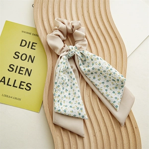 Detail of beige floral chiffon scrunchie with layered bow ribbon on wooden display