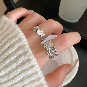 Detailaufnahme von silbernem asymmetrischem Blumenring und Lavaring an der Hand