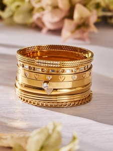 Détails de bracelets dorés multicouches avec zircons et gravures de cœur