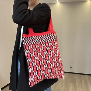 Detail of red knitted tote bag with geometric patterns and soft woven texture