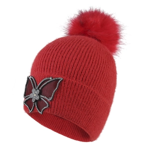 Red winter knit beanie with faux fur pom-pom and rhinestone butterfly decoration