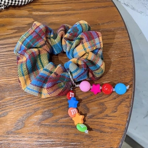 Rainbow plaid scrunchie with colorful beads and star charm on wooden background