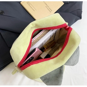 Draufsicht auf grüne Plüschtasche mit rotem Reißverschluss für Notizbuch und Make-up