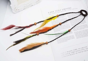 Detail of colorful feather hair extensions with wooden beads for bohemian styling