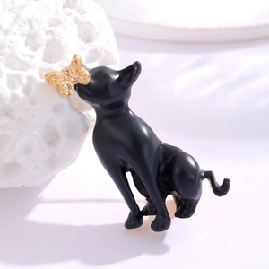 Close-up of black cat brooch featuring a golden butterfly detail on a soft background